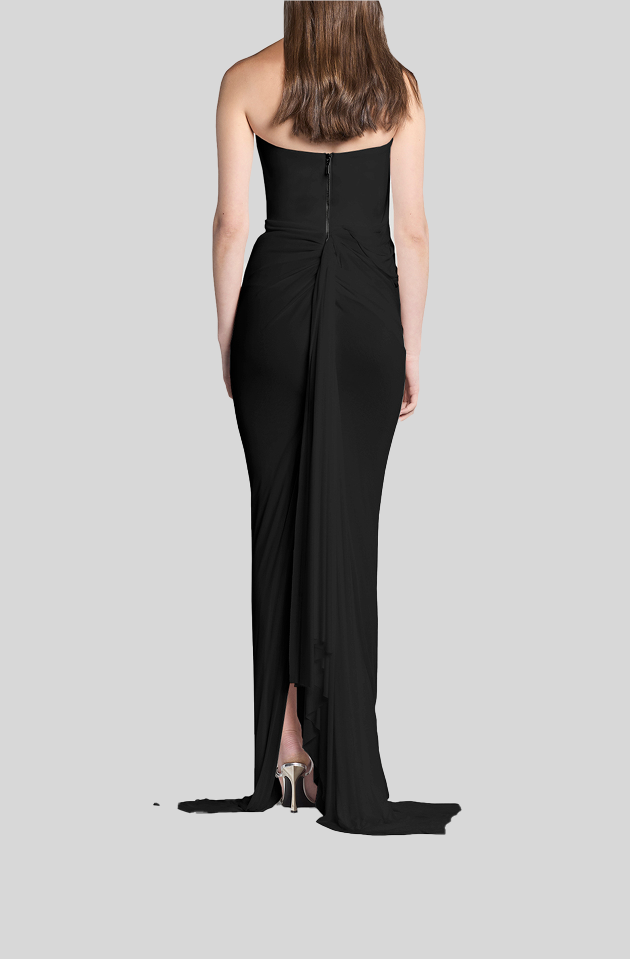 Woman wearing a black strapless gown with a slit on a gray background